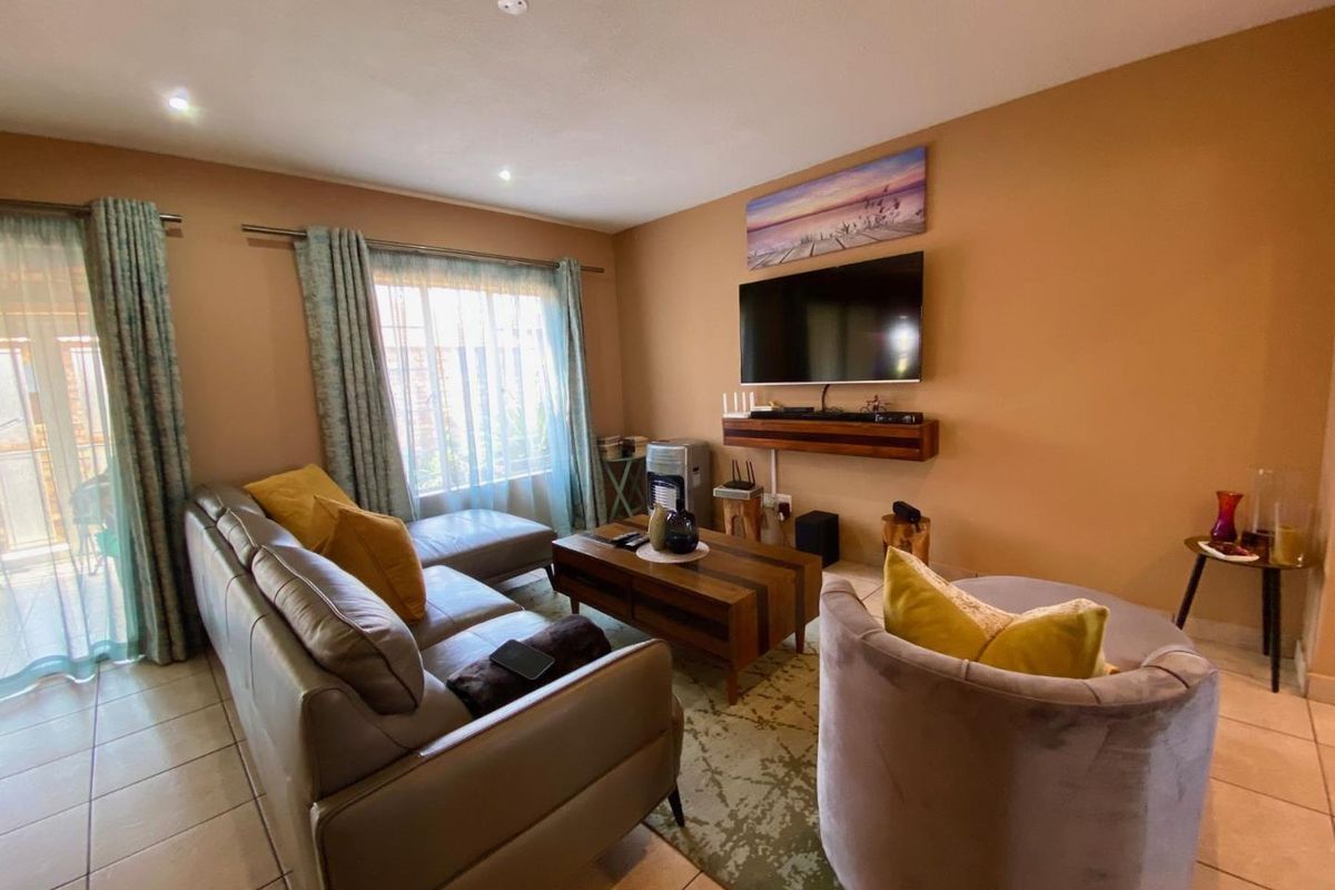 A comfortable living room featuring tiled flooring, recessed ceiling lighting, and a sliding door providing access to the outdoor area.