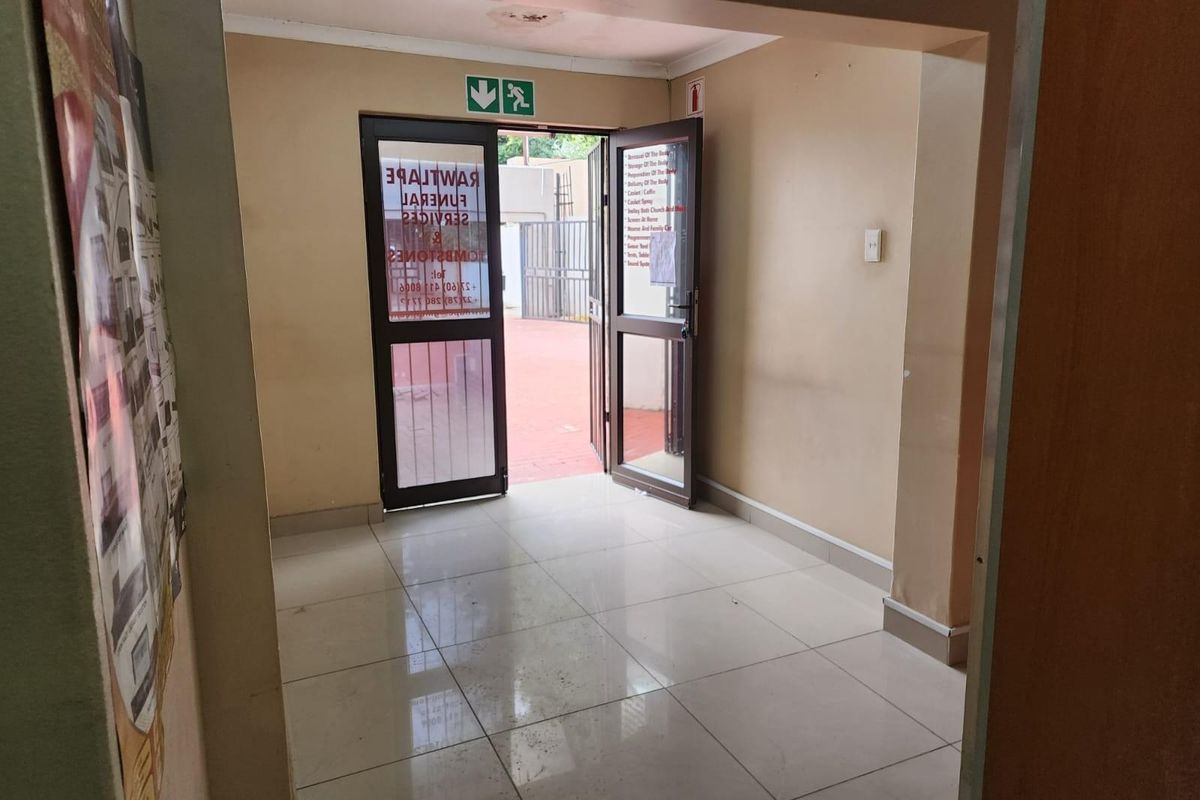 An interior entry area featuring tiled flooring, a double door leading to an outdoor space, and emergency exit signage.