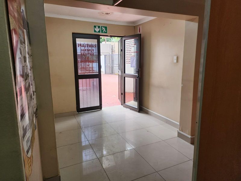 An interior entry area featuring tiled flooring, a double door leading to an outdoor space, and emergency exit signage.
