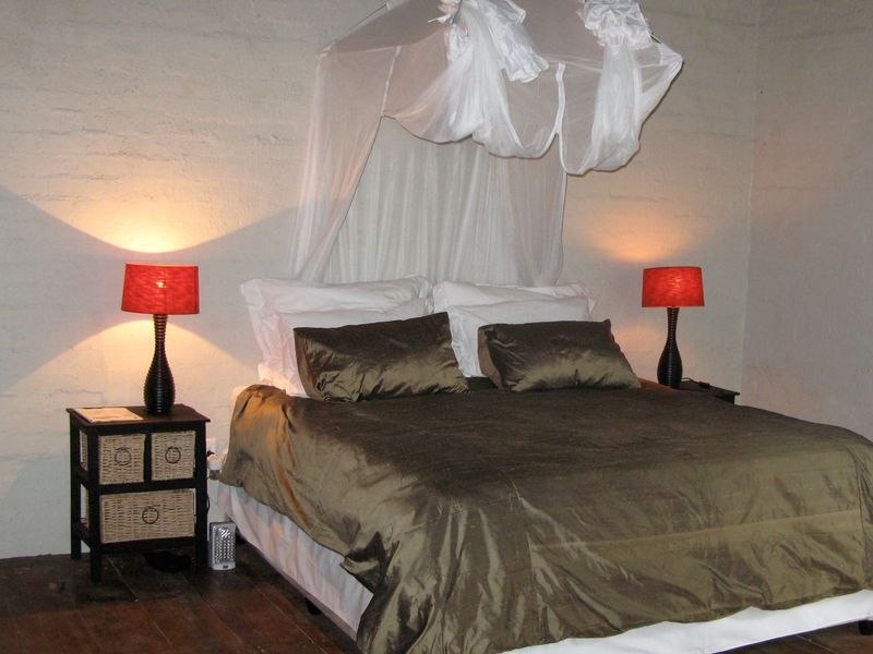 A bedroom featuring rustic exposed brick walls and timber flooring, providing a simple and functional space.