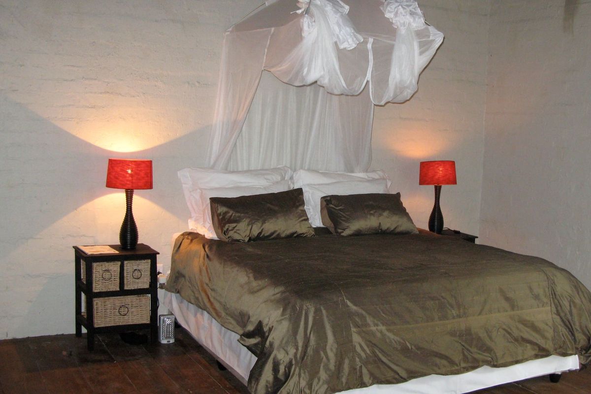 A bedroom featuring rustic exposed brick walls and timber flooring, providing a simple and functional space.