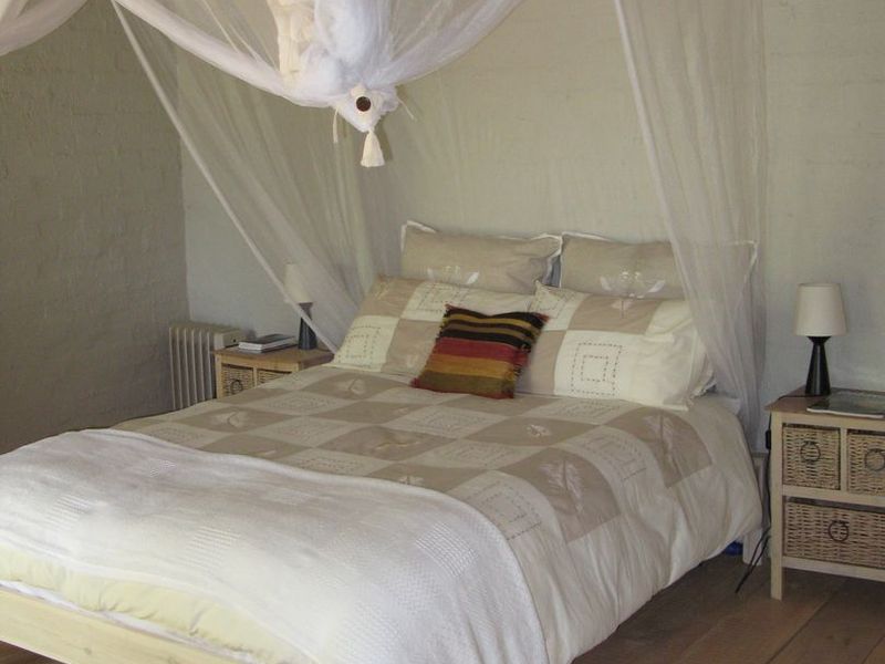 A bedroom featuring timber flooring and painted brick walls, creating a rustic and cozy atmosphere.