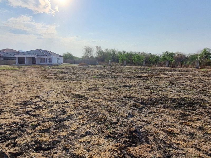 A wide-angle view of a vacant residential plot featuring cleared land and perimeter fencing, situated in a developed residential estate.