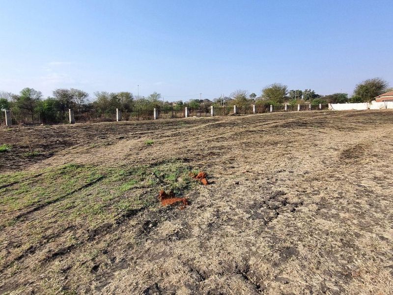 A vacant residential plot featuring perimeter fencing and concrete posts, offering a clear, level space ready for development.