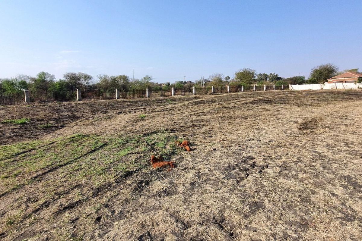 A vacant residential plot featuring perimeter fencing and concrete posts, offering a clear, level space ready for development.