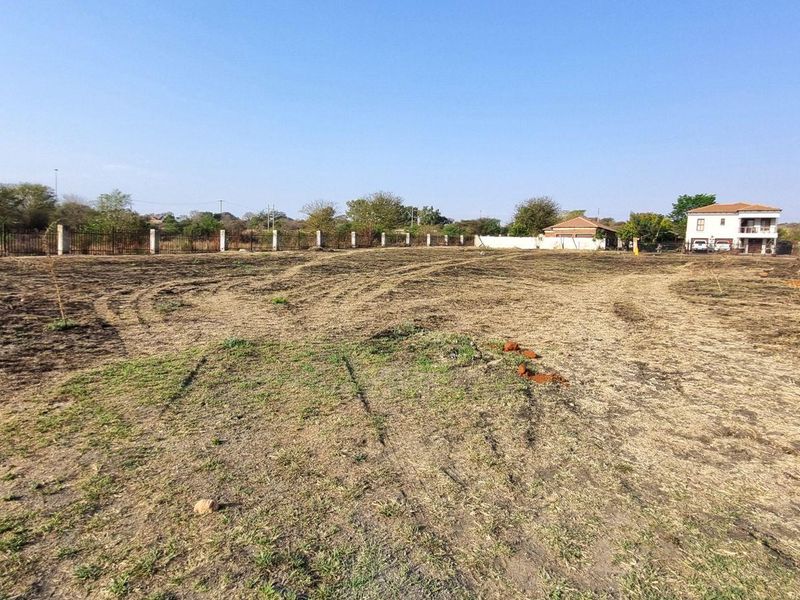A wide-angle view of a vacant residential plot featuring cleared land and perimeter fencing, ready for development.