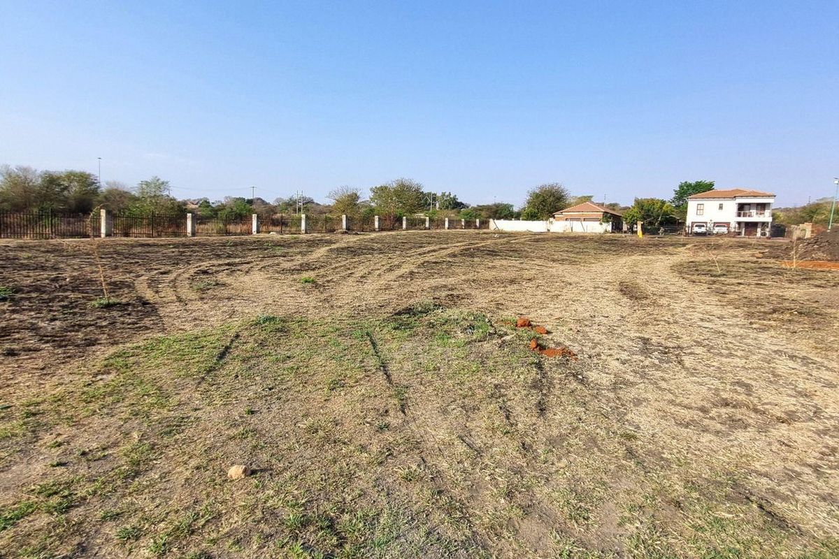 A wide-angle view of a vacant residential plot featuring cleared land and perimeter fencing, ready for development.