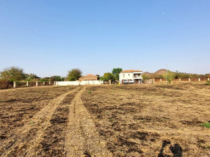 A wide-angle view of a vacant residential plot featuring perimeter fencing and concrete pillars, ready for development.