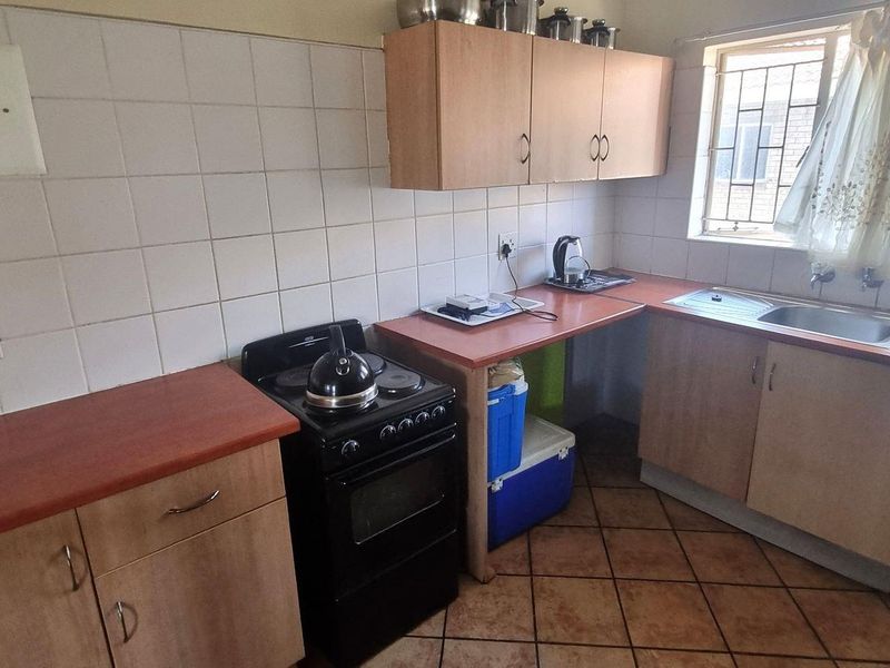A functional kitchen featuring laminate countertops, built-in cabinetry, a stainless steel sink, and tiled backsplash with ceramic floor tiles.