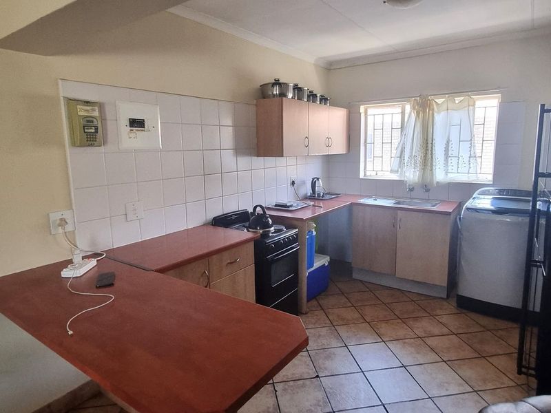 Functional kitchen featuring laminate countertops, tiled backsplash, built-in cabinetry, and tiled flooring, offering a practical layout for daily meal preparation.
