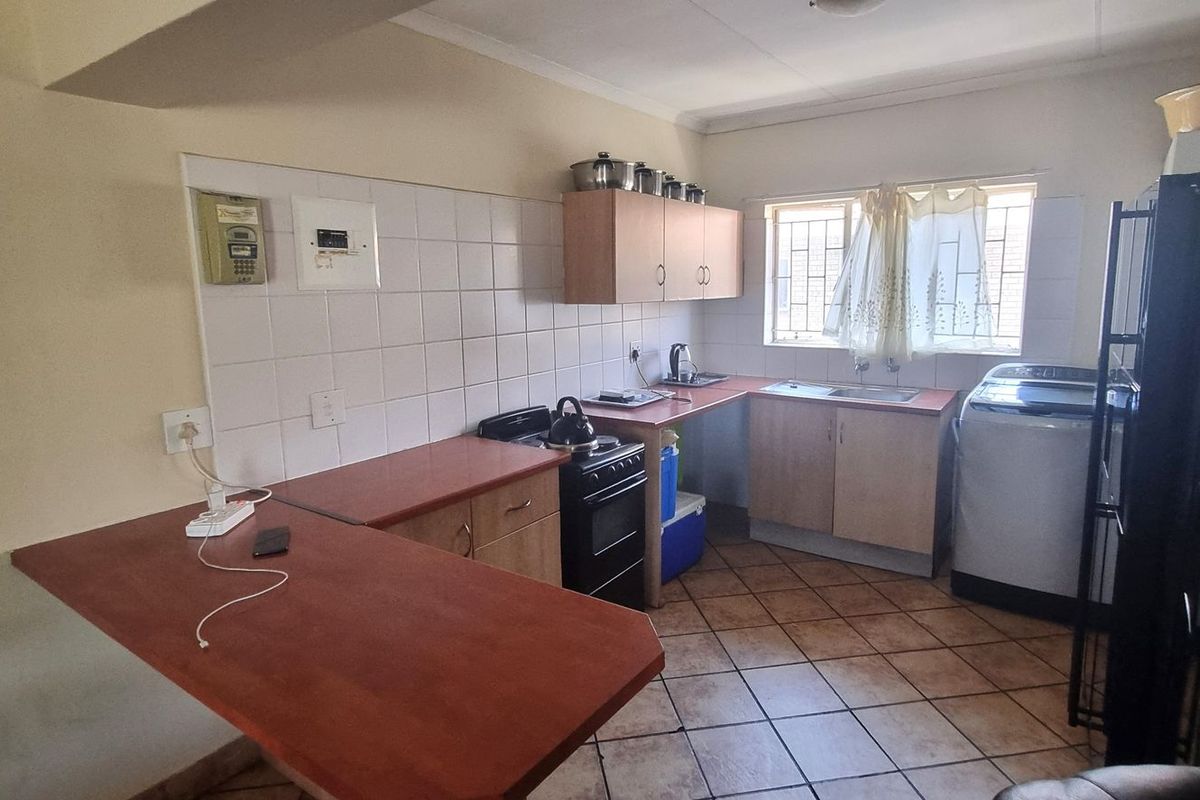 Functional kitchen featuring laminate countertops, tiled backsplash, built-in cabinetry, and tiled flooring, offering a practical layout for daily meal preparation.