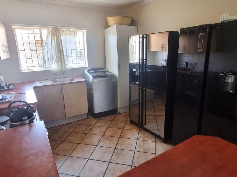Functional kitchen featuring laminate countertops, built-in cabinetry, tiled splashbacks, and tiled flooring, offering a practical layout for daily meal preparation.
