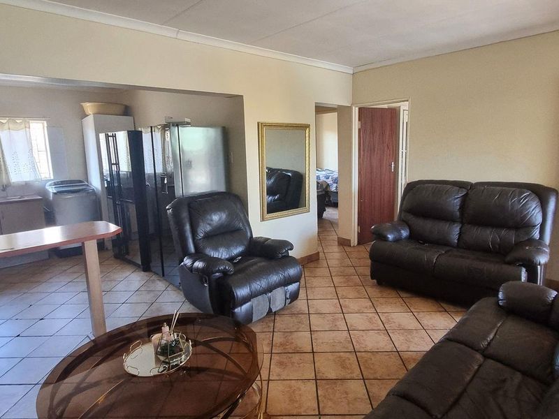 An open-plan living and kitchen area featuring tiled flooring, a breakfast bar, and functional kitchen cabinetry.