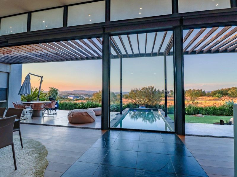 Modern open-plan living area featuring expansive sliding glass doors that open onto a covered patio with a plunge pool and scenic landscape views.