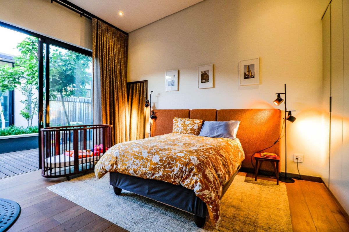 A well-maintained bedroom featuring timber flooring, built-in wardrobes, and a large sliding glass door providing direct access to an outdoor patio area.