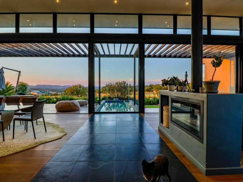 Modern open-plan living area featuring a built-in fireplace, expansive floor-to-ceiling glass doors, and seamless transition to an outdoor patio and pool area.