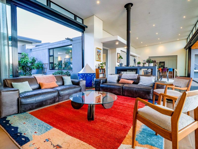 Spacious open-plan living area featuring a modern freestanding fireplace, high ceilings, and expansive sliding glass doors that open to an outdoor patio.