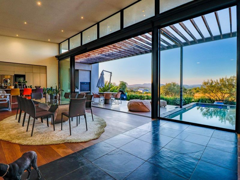 Spacious open-plan living area featuring seamless indoor-outdoor flow through large sliding glass doors to a covered patio, swimming pool, and scenic landscape views.