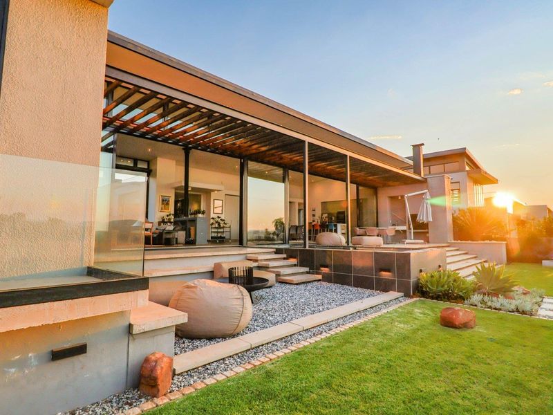 Modern outdoor patio area featuring a timber pergola, glass sliding doors, and a seamless transition to the landscaped garden and lawn.
