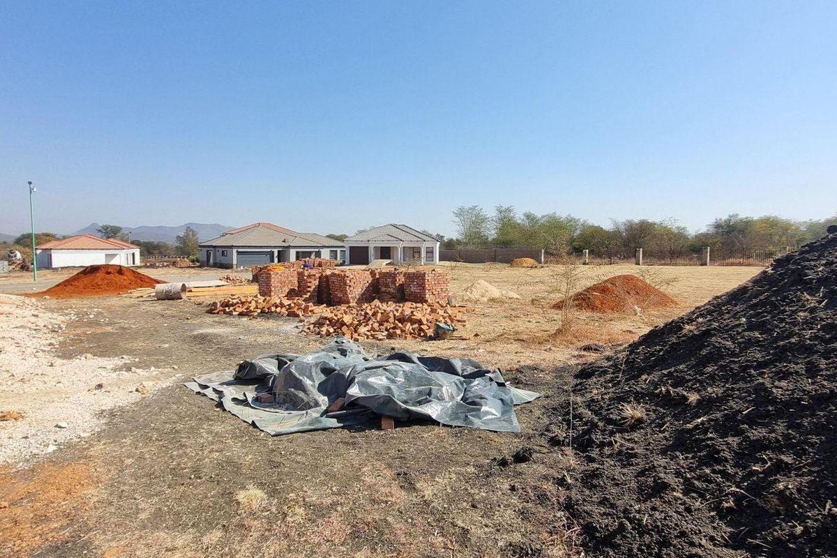 A view of a residential construction site featuring exposed brickwork, piles of building materials, and surrounding neighborhood development.