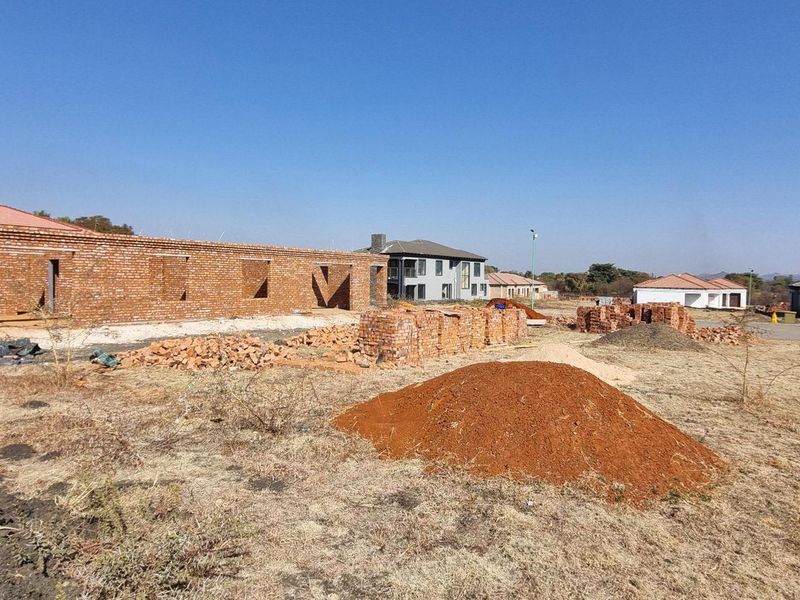 A residential plot featuring a partially constructed brick building structure amidst an active development site.
