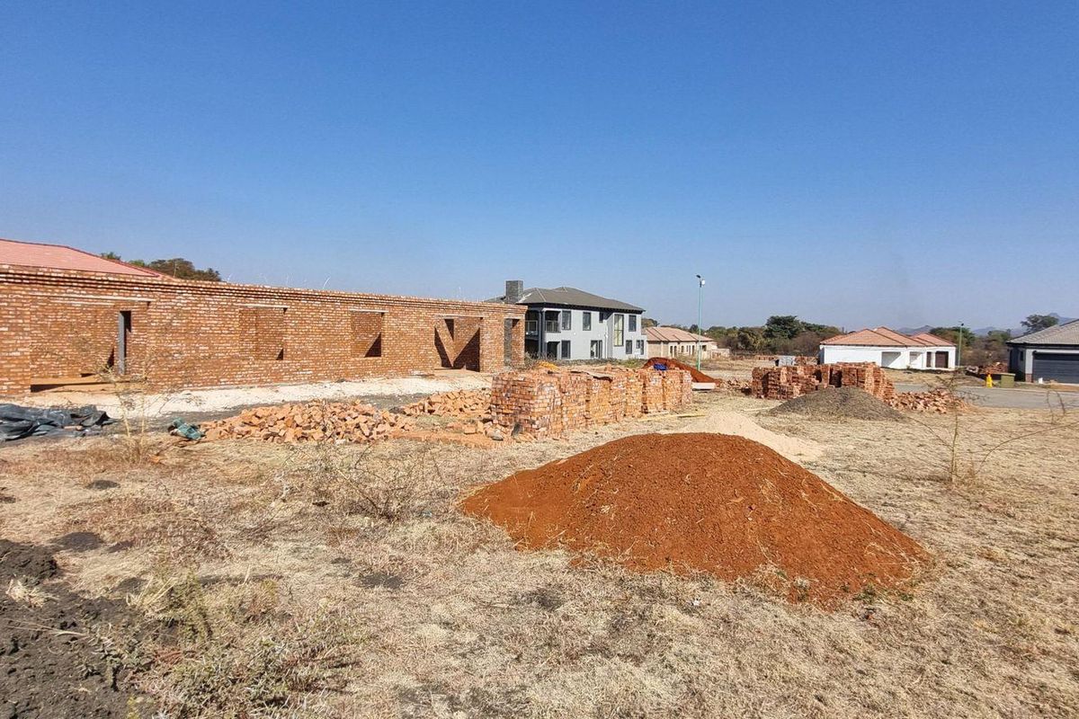 A residential plot featuring a partially constructed brick building structure amidst an active development site.