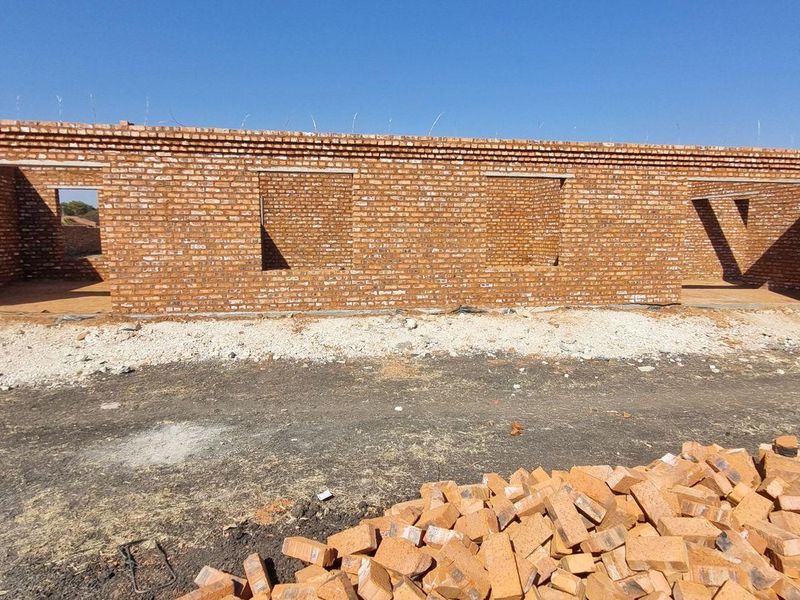 A view of a residential property under construction, featuring a face brick facade with open window and door frames.