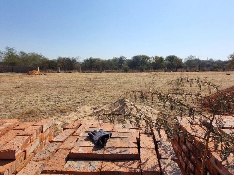 A wide-angle view of a vacant residential plot featuring cleared land and perimeter fencing, ready for development.