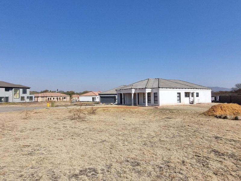 A wide-angle view of a vacant residential plot in a developing estate, featuring surrounding modern homes and clear boundary lines.