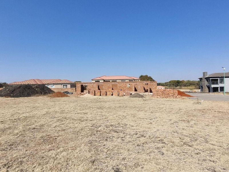 A vacant residential plot featuring ongoing brickwork construction, situated in a developing neighborhood with surrounding residential properties.