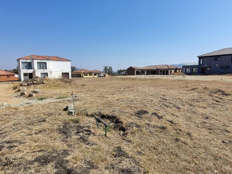 A vacant residential plot of land situated in a developed estate, featuring clear boundaries and access to utility connections.