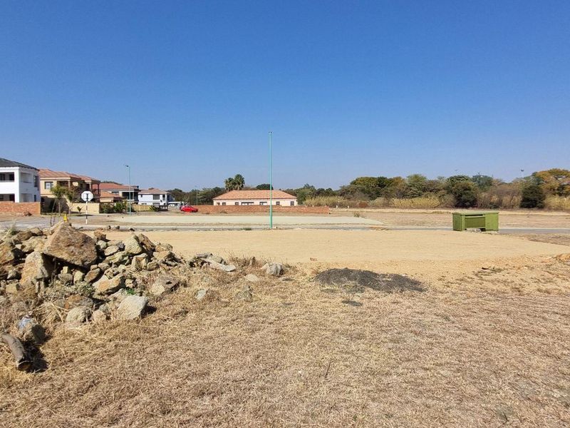 A vacant residential plot of land featuring cleared ground, street access, and surrounding neighborhood infrastructure.