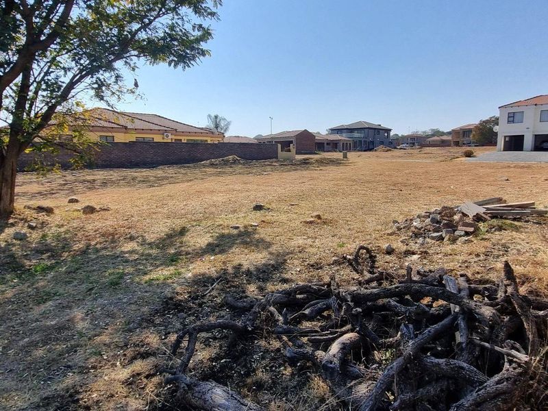 A vacant residential plot featuring a boundary wall and mature tree, offering a clear space for future development in a established neighborhood.