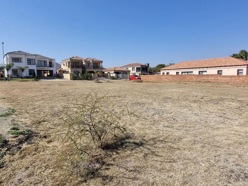 A vacant residential plot of land situated in a developed neighborhood, featuring a brick boundary wall and clear access to surrounding residential properties.