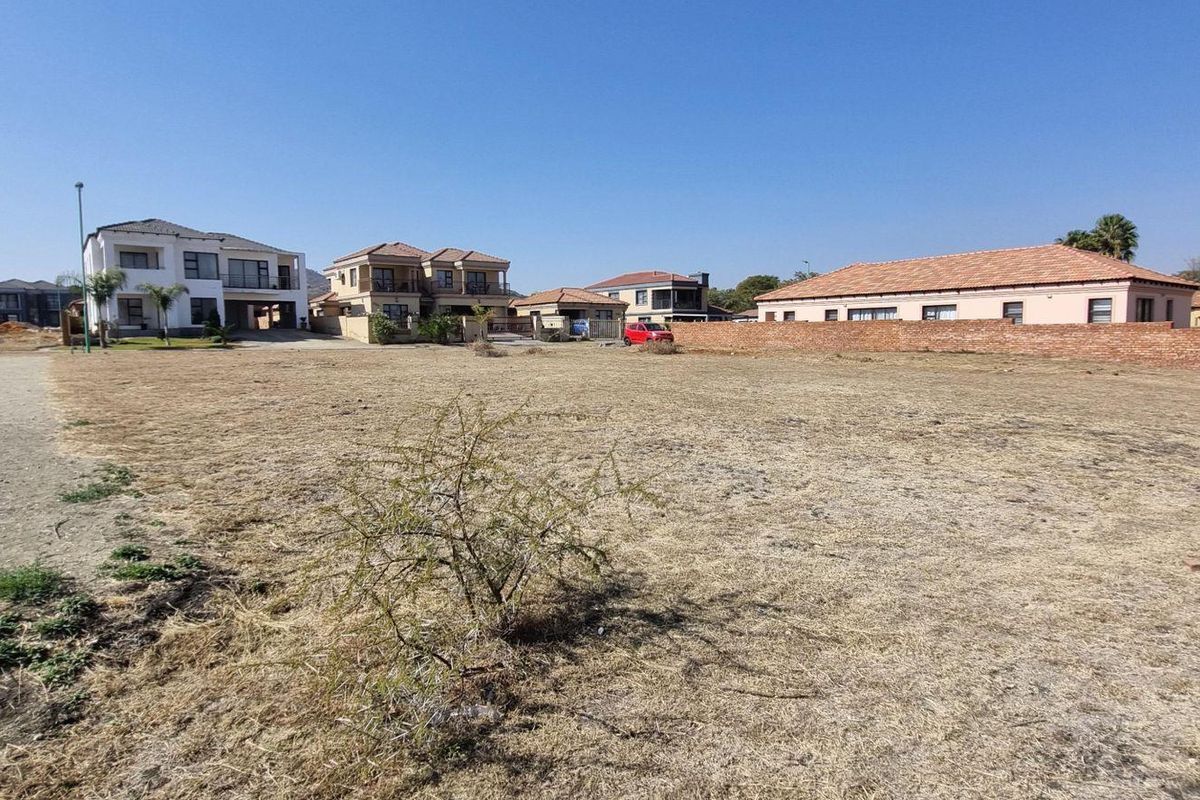 A vacant residential plot of land situated in a developed neighborhood, featuring a brick boundary wall and clear access to surrounding residential properties.