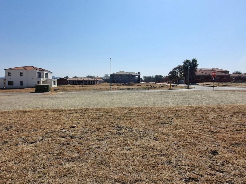 A wide-angle view of a vacant residential plot in a developed estate, featuring surrounding homes and established street infrastructure.