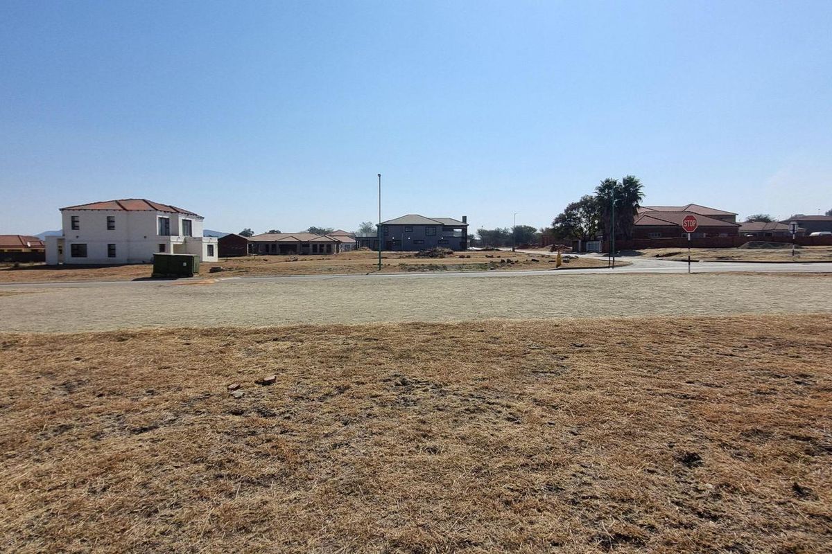 A wide-angle view of a vacant residential plot in a developed estate, featuring surrounding homes and established street infrastructure.