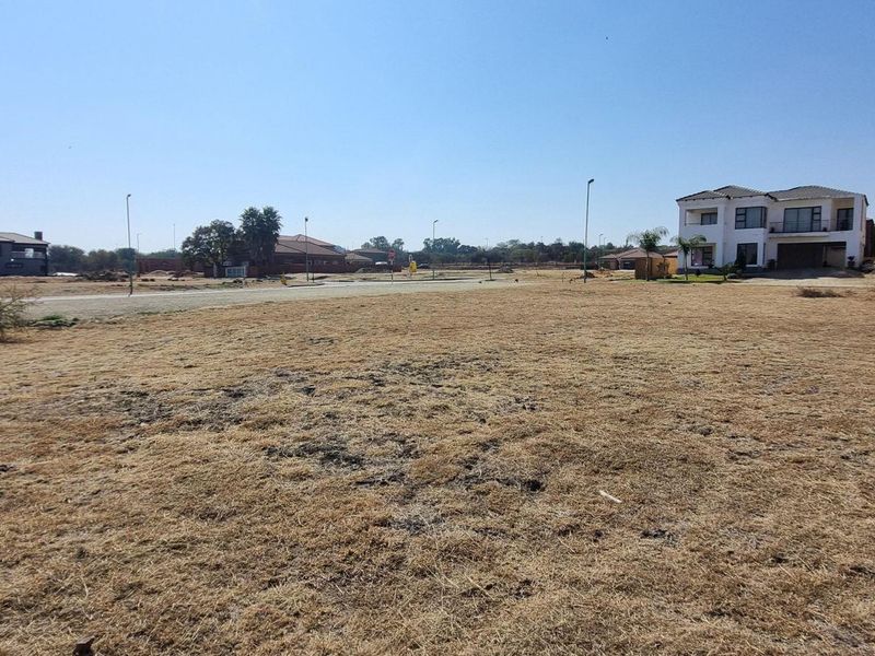A vacant residential plot situated in a developed estate, featuring level ground with established street infrastructure and surrounding residential properties.