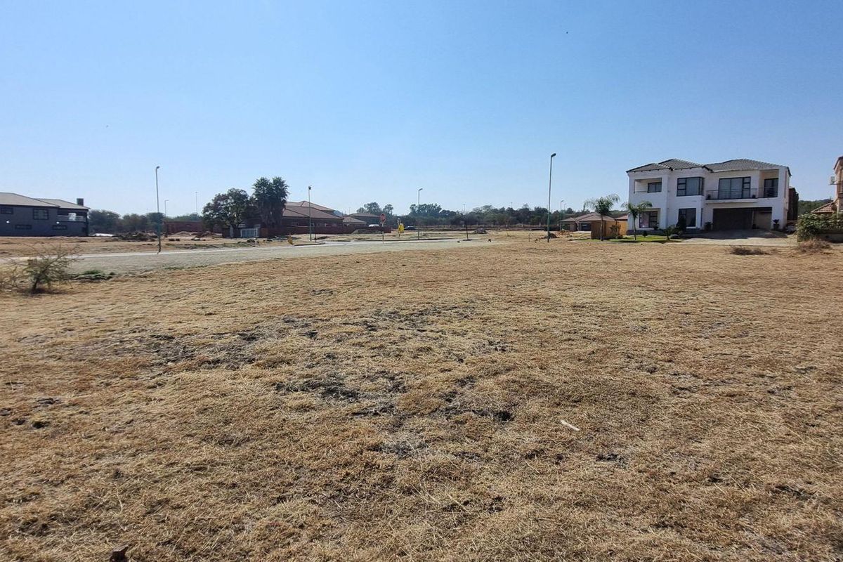 A vacant residential plot situated in a developed estate, featuring level ground with established street infrastructure and surrounding residential properties.