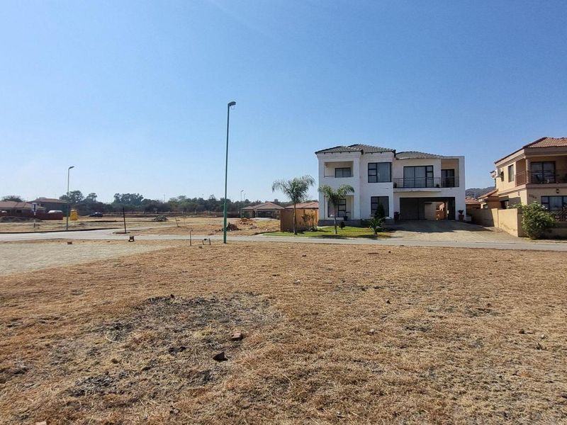 A vacant residential plot situated in a developed estate, featuring street access and proximity to existing modern residential properties.