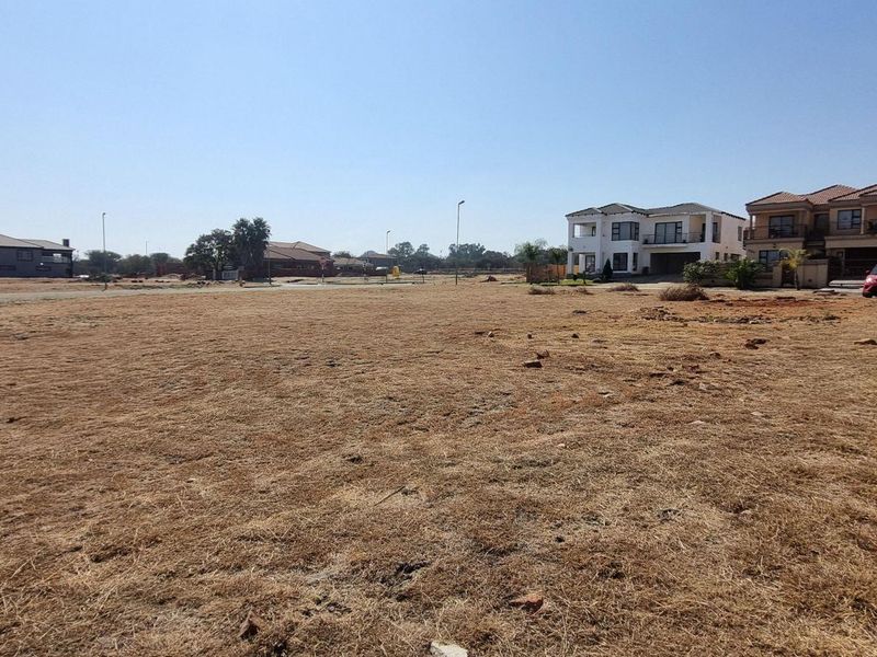 A vacant residential plot featuring a brick boundary wall, situated in a developed neighborhood with surrounding residential properties.