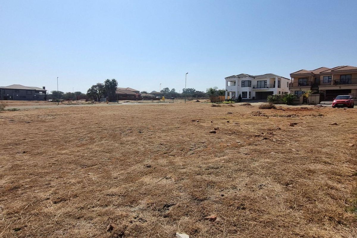 A vacant residential plot featuring a brick boundary wall, situated in a developed neighborhood with surrounding residential properties.