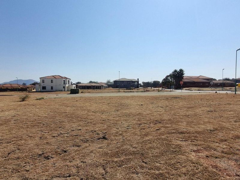 A wide-angle view of a vacant residential plot in a developed estate, featuring surrounding homes and established street infrastructure.