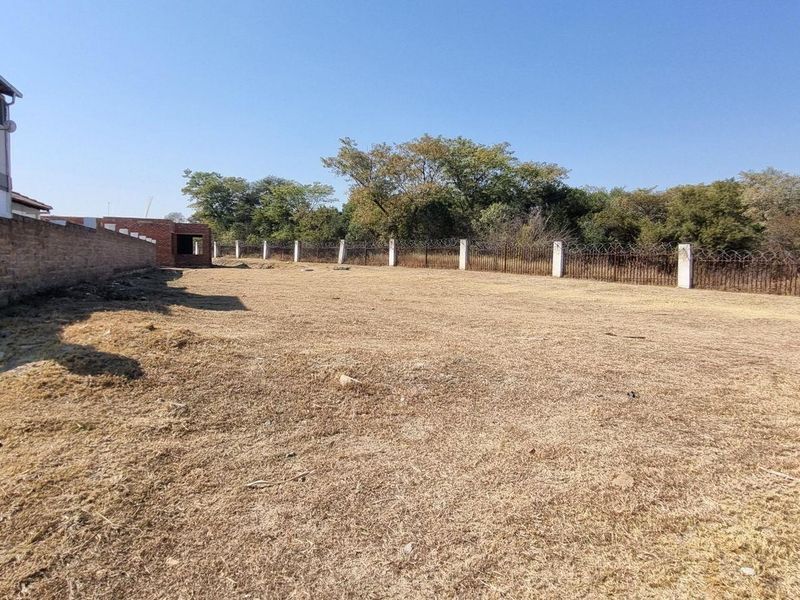 A spacious, level residential plot featuring a perimeter brick wall and secure fencing, offering a blank canvas for future development.