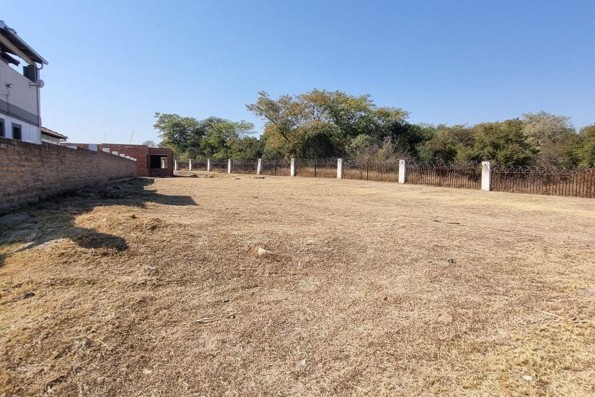 A spacious, level residential plot featuring a perimeter brick wall and secure fencing, offering a blank canvas for future development.