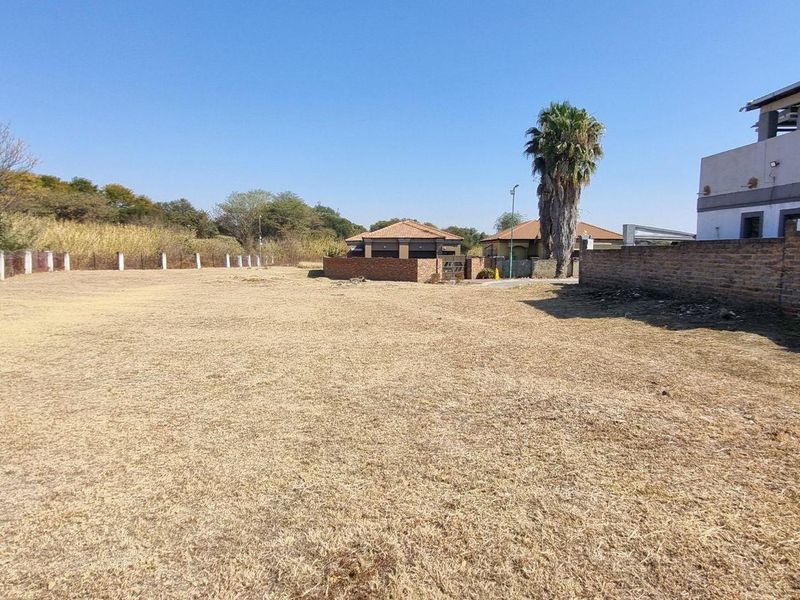 A vacant residential plot featuring a brick boundary wall and perimeter fencing, offering a clear space for potential development.