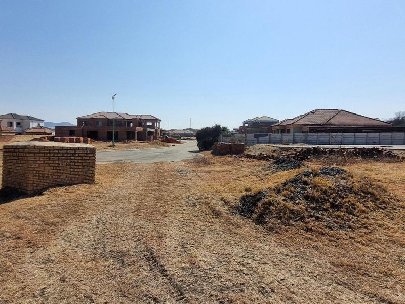 Vacant residential land in a developing estate, featuring road access and surrounding residential construction.