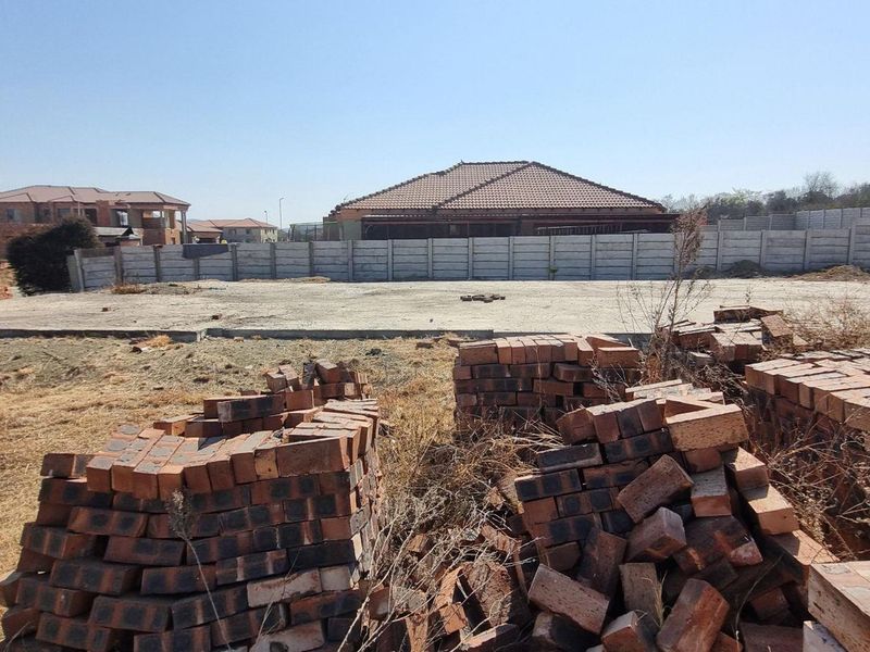 A vacant residential plot featuring a prepared concrete slab foundation and perimeter boundary walling, ready for construction.