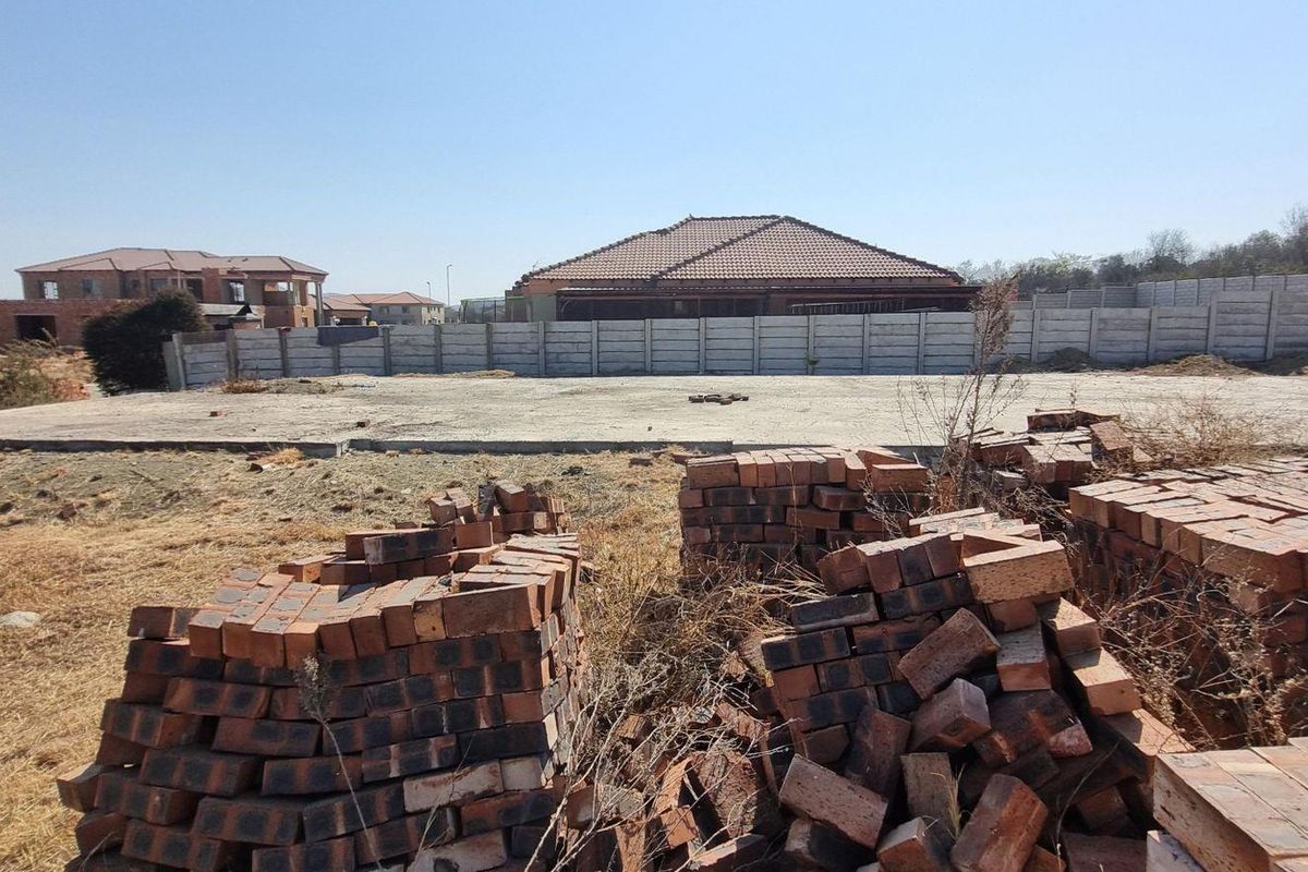 A vacant residential plot featuring a prepared concrete slab foundation and perimeter boundary walling, ready for construction.