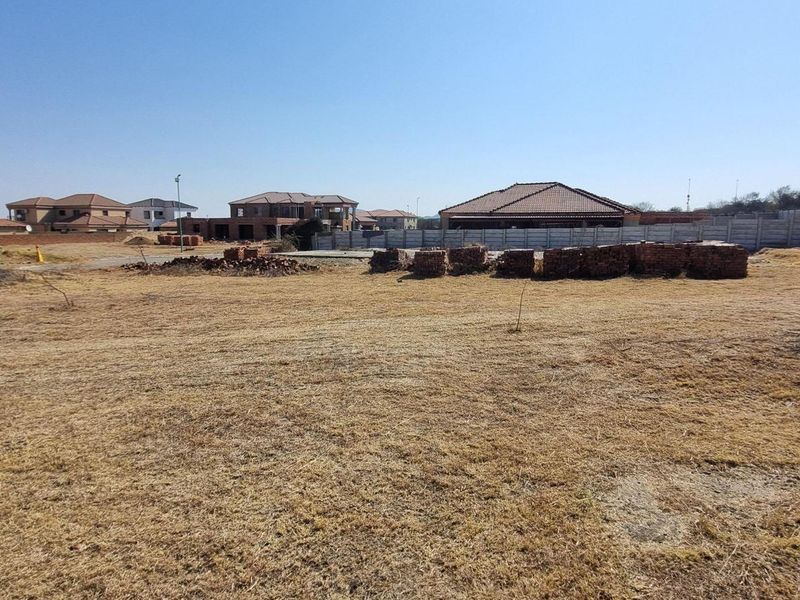 A vacant residential plot featuring a precast concrete boundary wall, situated in a developed neighborhood with surrounding residential properties.